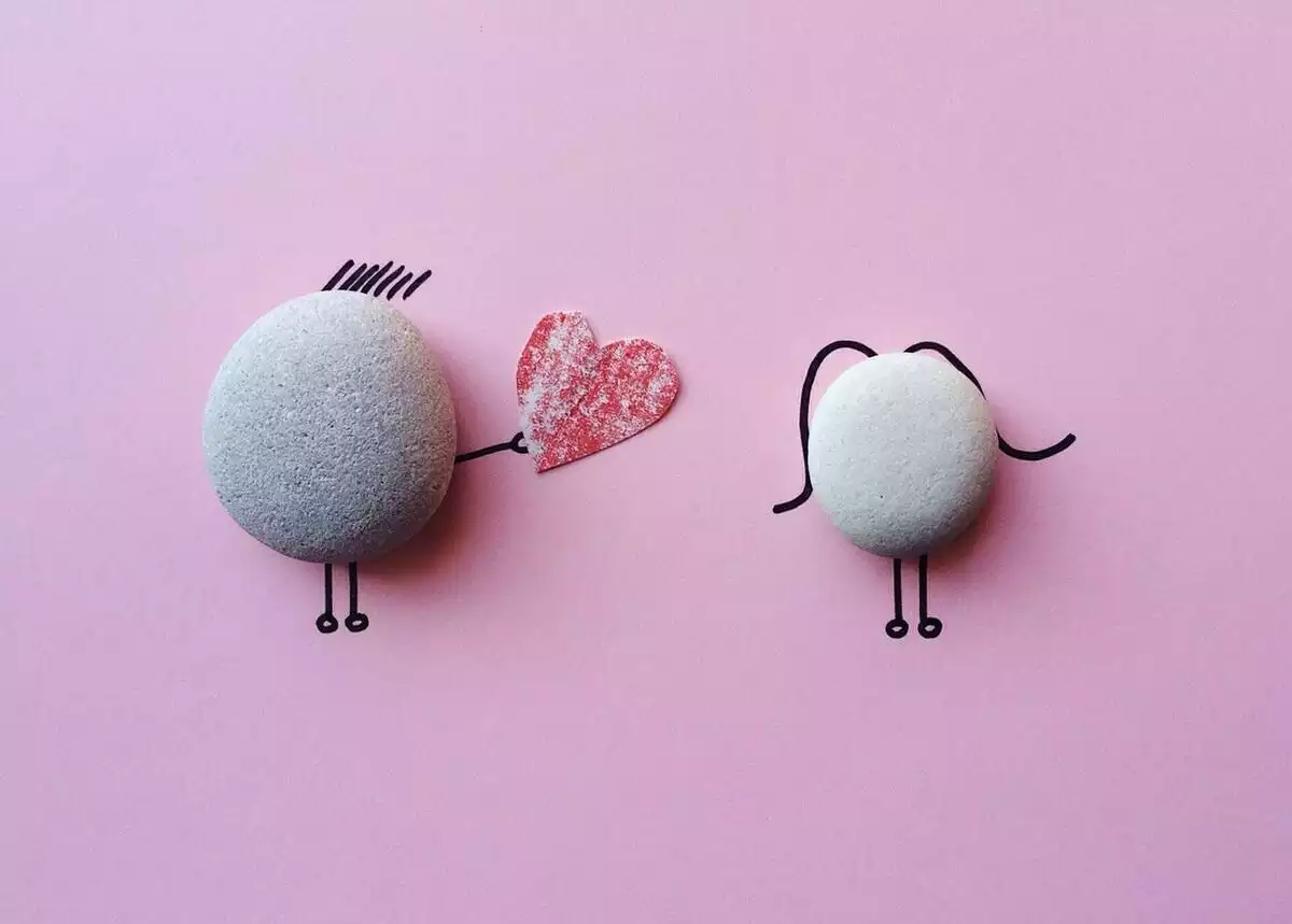 Représentation de deux pierres sur fond rose s'offrant un coeur