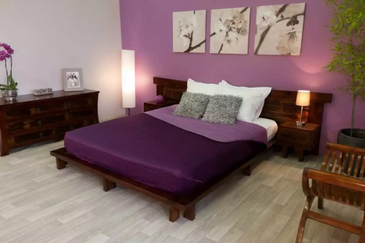 Lit aux draps violets dans une chambre violette peu éclairée