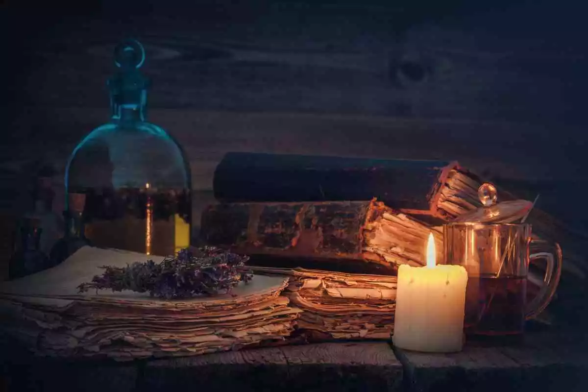 Une table avec des livres, des herbes, des potions et une bougie allumée
