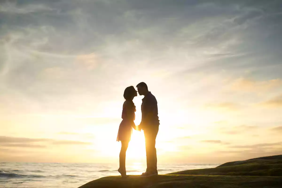 Un couple s'embrassant avec le coucher de soleil en arrière-plan