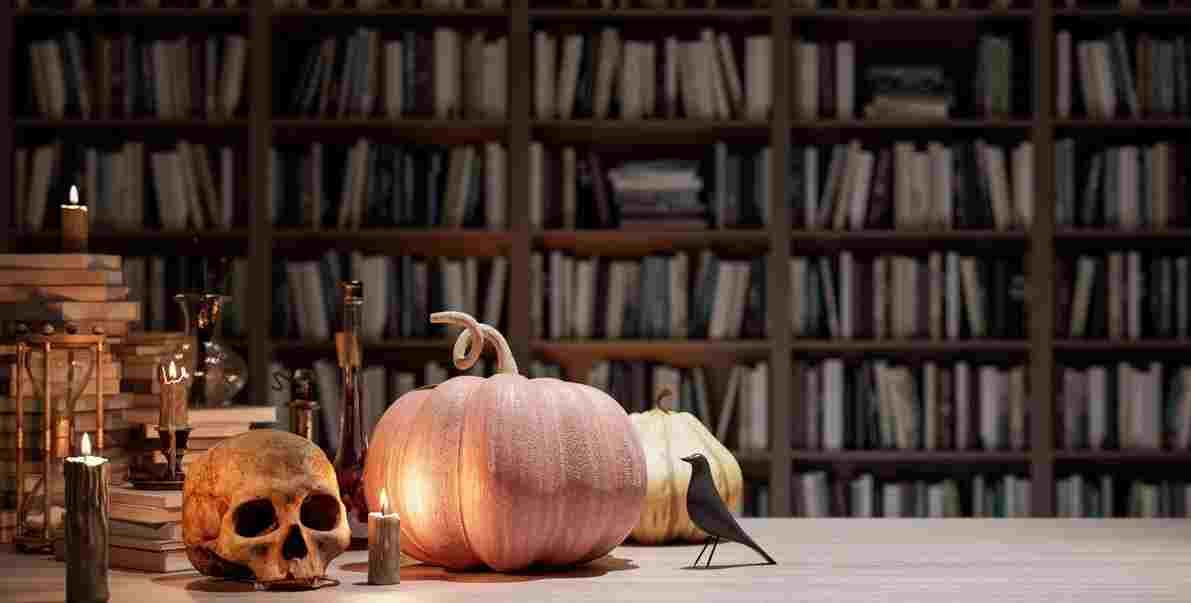 Une table avec une citrouille, un crâne et un oiseau noir
